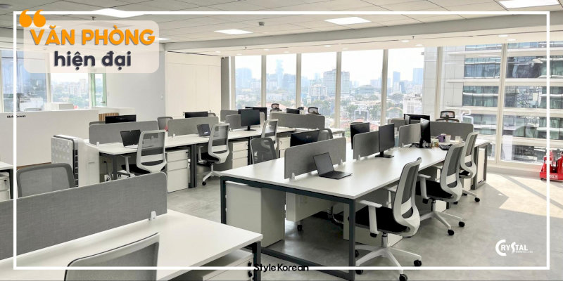Văn phòng coworking hiện đại, bàn làm việc cá nhân ngăn nắp, ghế xoay thoải mái và không gian làm việc chung sáng sủa với cửa sổ lớn.