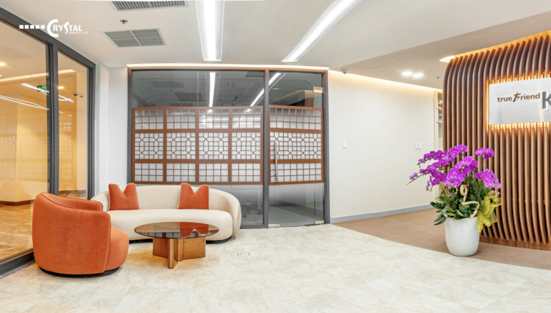 Sảnh chờ văn phòng ấm áp, sofa trắng kem hiện đại, ghế đơn cam nổi bật và bình hoa lan tím trang nhã.