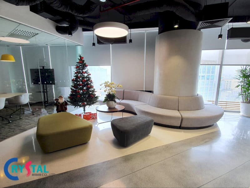 Khu vực sảnh văn phòng trang trí Giáng Sinh, sofa cong màu xám hiện đại, cây thông Noel lấp lánh và ông già Noel