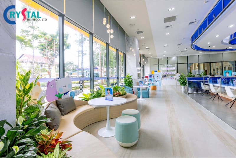 Không gian vui chơi trẻ em sinh động, ghế sofa cong êm ái, bàn tròn nhỏ xinh xắn và nhiều cây xanh trang trí tươi mát gần cửa sổ lớn.