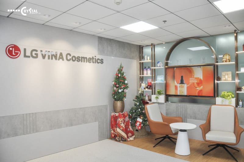 hu vực lễ tân trang nhã của LG Vina Cosmetics với logo nổi bật, không gian trang trí ấm áp mùa Giáng Sinh và khu vực chờ với ghế da và màn hình quảng cáo sản phẩm.