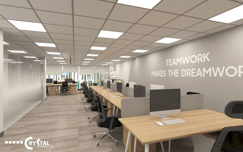 Văn phòng làm việc mở hiện đại với bàn dài, ghế xoay và tường slogan “Teamwork makes the dream work”.