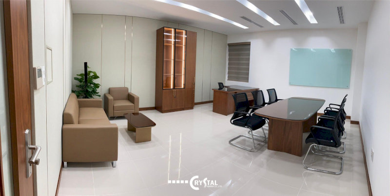 Phòng họp kết hợp khu tiếp khách với bàn họp gỗ, ghế chân quỳ và sofa nâu hiện đại.