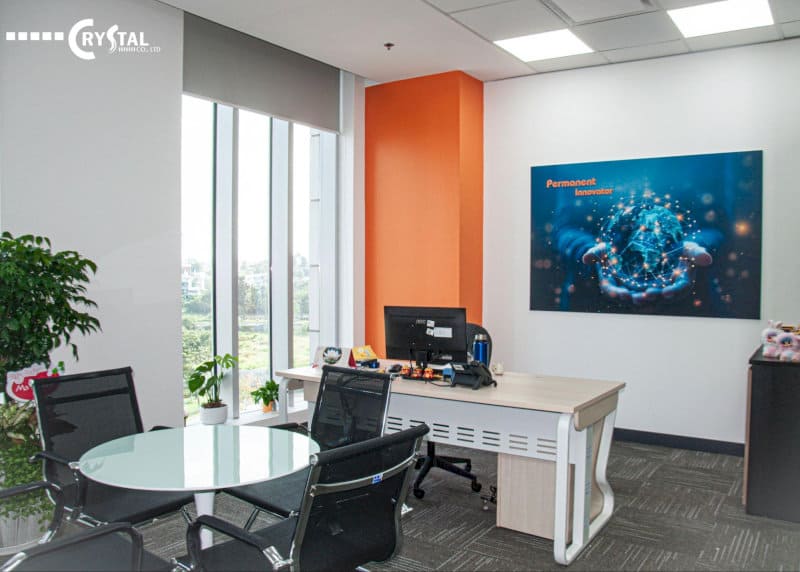Nội thất văn phòng hiện đại với bức tường màu xanh lam và trắng, logo CRYSTAL và một cây cảnh, tạo không gian làm việc tươi mới.