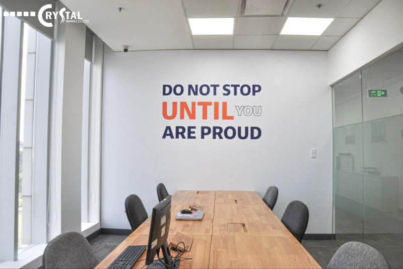 Bức tường văn phòng với hình ảnh đồ họa vinyl và dòng chữ "DO NOT STOP UNTIL YOU ARE PROUD".