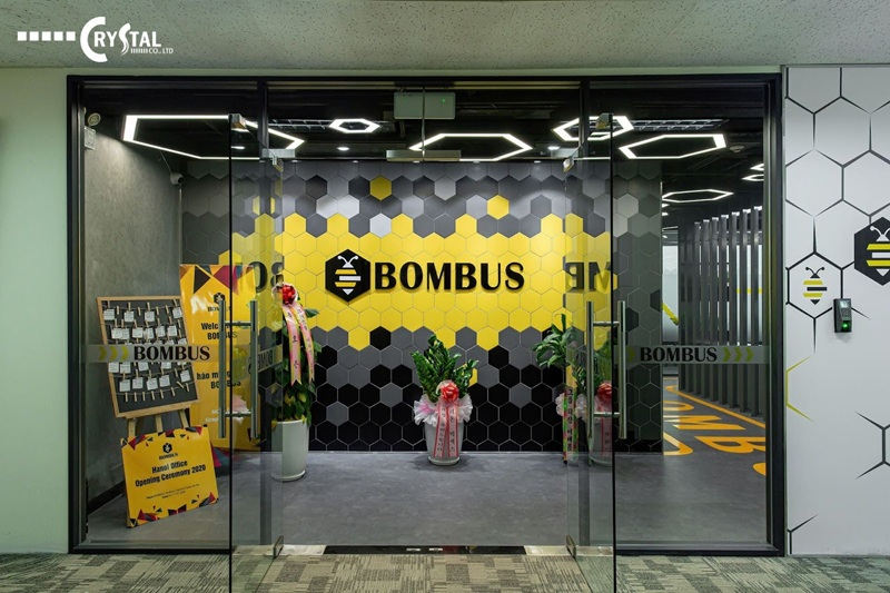 Lối vào văn phòng Bombus Hà Nội hiện đại với thiết kế tổ ong màu vàng đen và cửa kính trong suốt