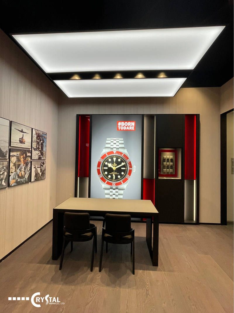 Showroom sang trọng trưng bày hình ảnh đồng hồ Tudor lớn, với tủ kính trưng bày sản phẩm và khu vực tư vấn khách hàng
