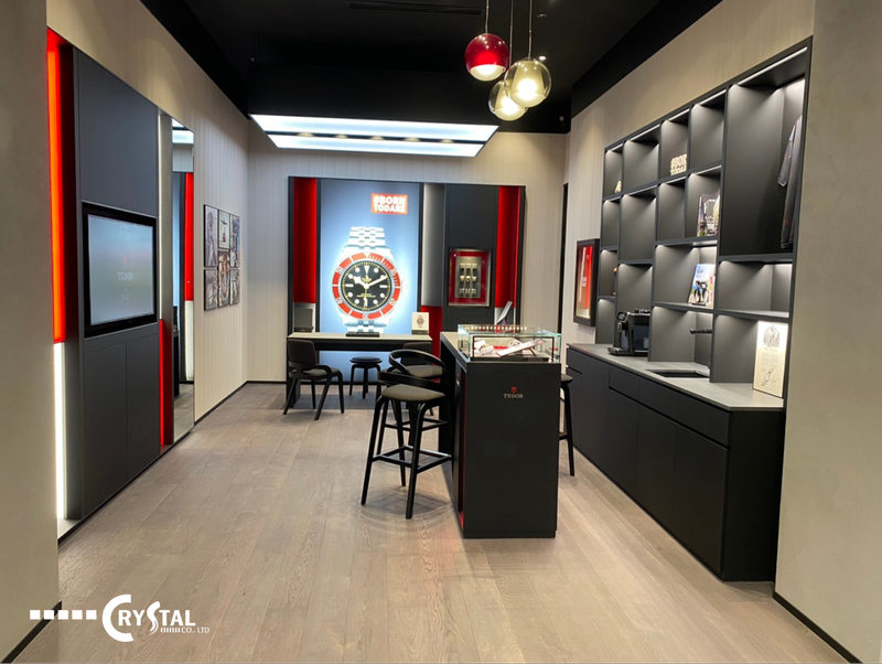 Showroom sang trọng với sàn nhà sử dụng gỗ sáng màu, tủ trưng bày sản phẩm đen và điểm nhấn đèn đỏ