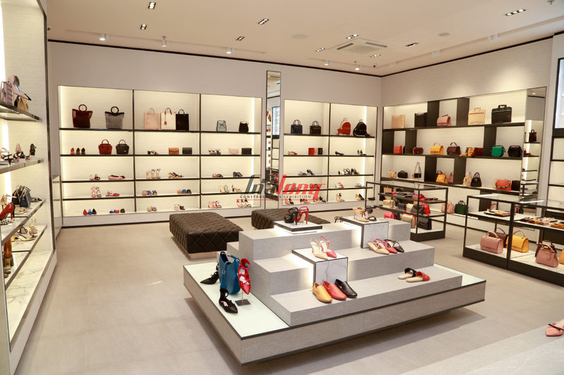 Showroom giày dép túi xách hiện đại, sang trọng với các kệ trưng bày sản phẩm được chiếu sáng, khu vực ngồi nghỉ