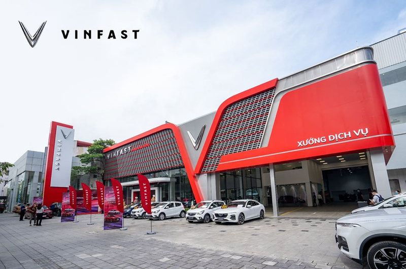 Showroom ô tô VinFast 3S hiện đại với kiến trúc độc đáo màu đỏ và xám, trưng bày nhiều mẫu xe VinFast trắng
