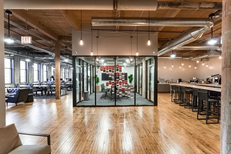 Không gian coworking phong cách công nghiệp với phòng họp kính nổi bật ở vị trí trung tâm.