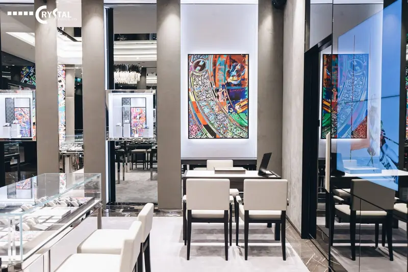 Một bức tranh nghệ thuật đầy màu sắc đóng vai trò là phông nền ấn tượng cho khu vực tư vấn với nội thất tối giản và hiện đại. Sự kết hợp táo bạo này tạo nên một không gian bán hàng vừa sang trọng, vừa độc đáo và đậm chất nghệ sĩ.