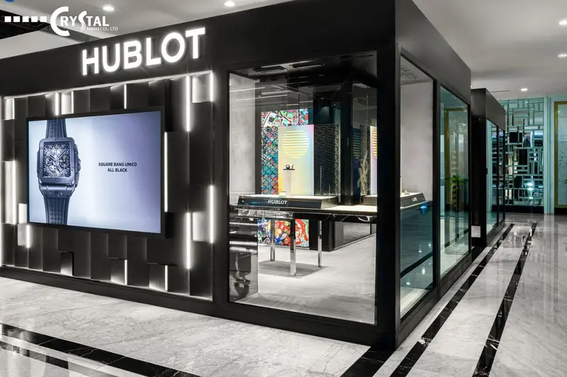 Mặt tiền boutique là một khối kiến trúc tối giản nhưng đầy quyền lực với tông màu đen, các chi tiết ánh sáng sắc nét, tích hợp màn hình lớn và sử dụng vách kính trong suốt.