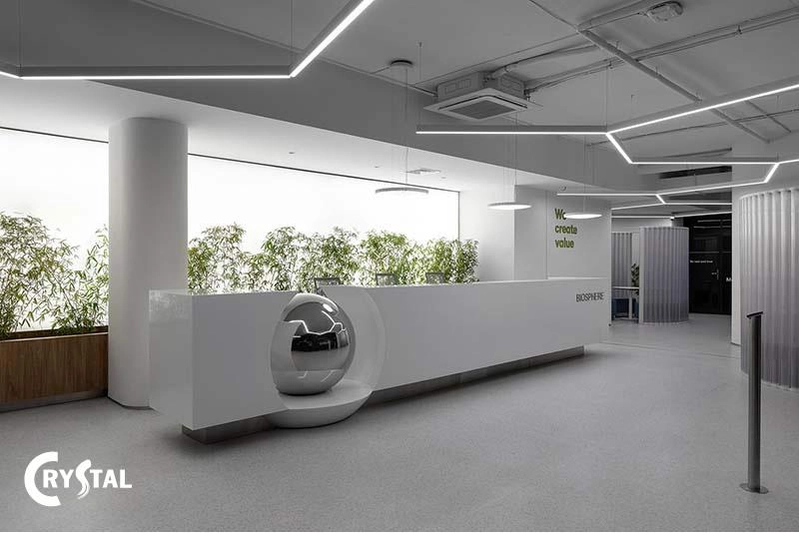 Khu lễ tân tối giản với mặt quầy đá trắng và các cụm cây xanh tạo điểm nhấn tự nhiên (Nguồn: Deco Crystal)