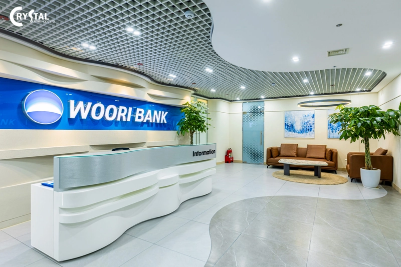 Khu lễ tân với quầy reception cong, logo nổi chiếu sáng và hệ trần ấn tượng (Nguồn: Deco Crystal)