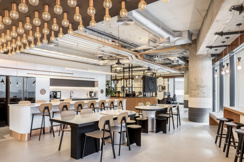 Intentionally exposed copper piping and copper-tinged Edison bulbs introduce rich warmth, softening the cold concrete shell of this modern tech lounge (Source: Internet)
