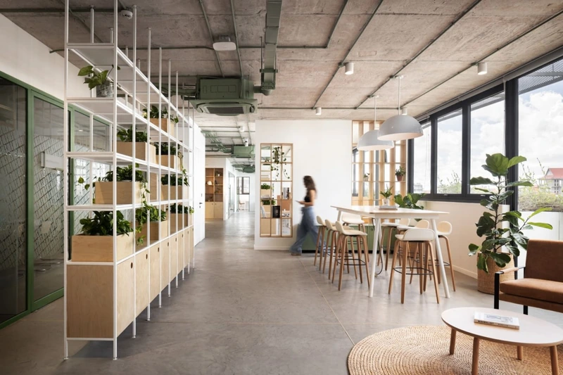 Exposed concrete walls contrast with bespoke birch plywood joinery, creating physical and visual zoning that defines focus areas within a vast open layout (Source: Internet)