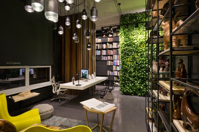 A lush vertical garden climbs a raw concrete wall, serving as a powerful sensory focus that actively reduces stress within an industrial office (Source: Internet) 