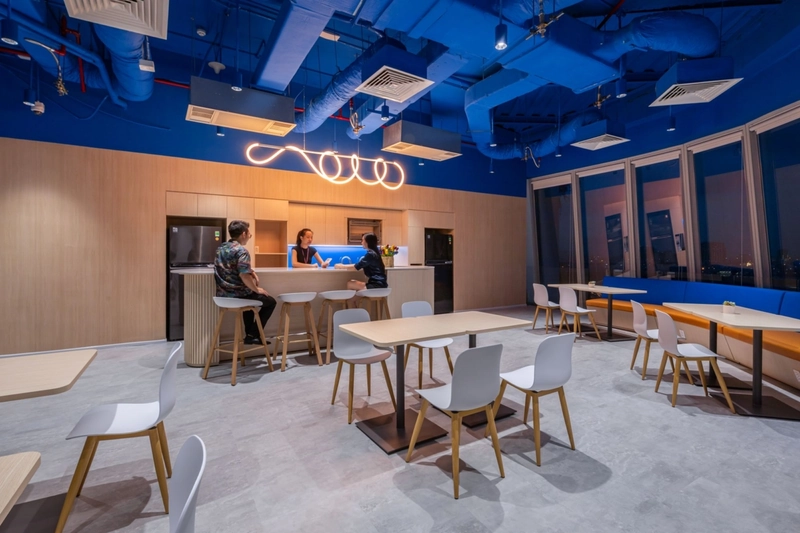 Khu pantry văn phòng thiết kế hiện đại với quầy bếp đầy đủ, bàn cao và ánh sáng ấm - không gian tái tạo năng lượng trong giờ làm (Nguồn: Internet)