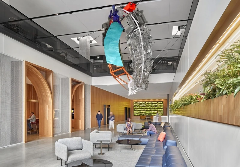This workspace features a striking, suspended biophilic sculpture crafted from reclaimed timber and natural moss, complemented by warm, slatted-wood walls and arched portals.