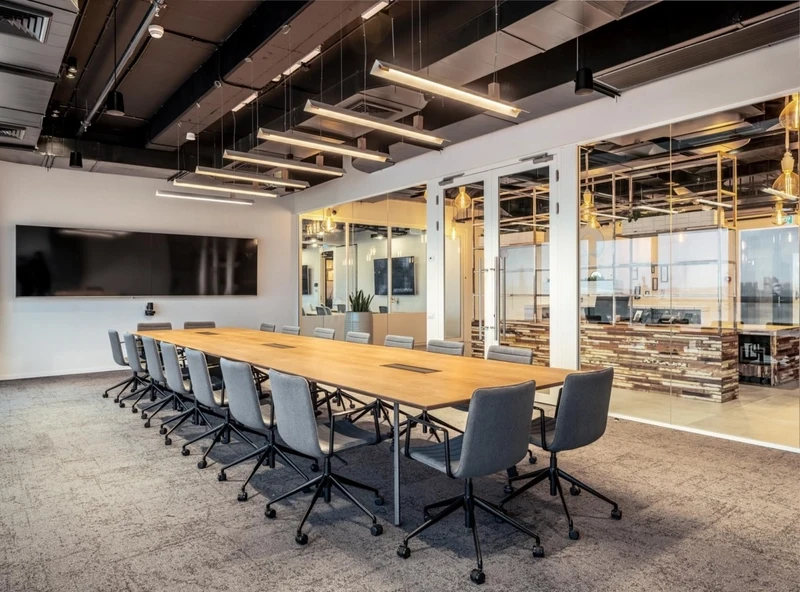 Integrated furniture with built-in charging pads and seamless AV connectivity for hybrid meetings, a modern feature of workspace interior design