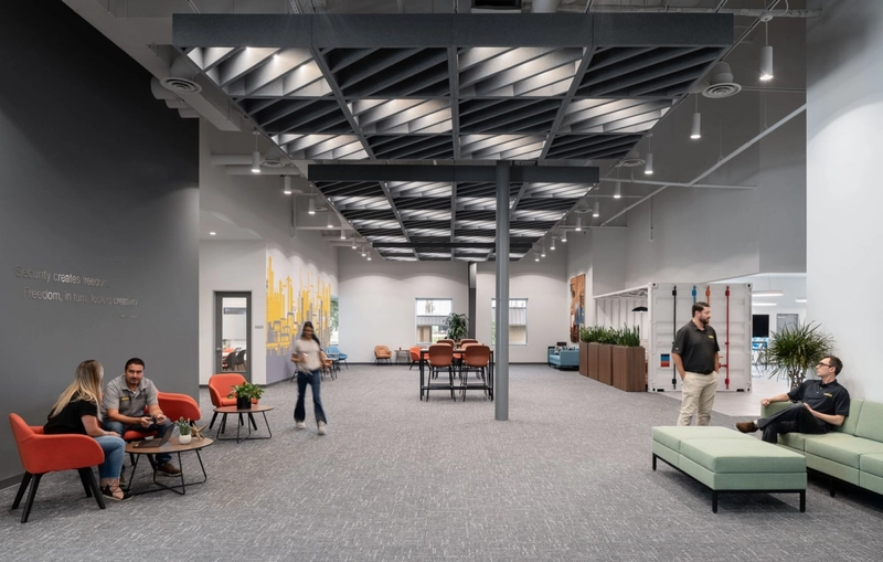 Suspended geometric acoustic baffles break up sound waves in high-ceiling environments, maintaining crystal-clear focus within the bustling workspace