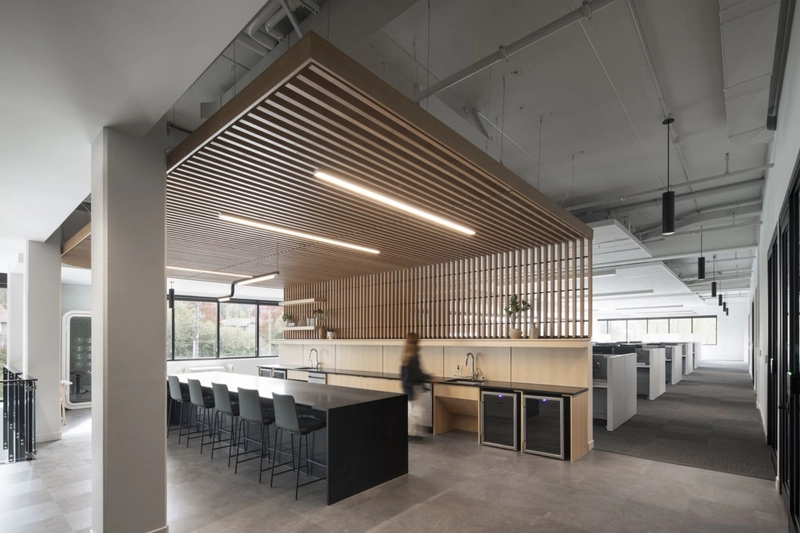 An acoustic grid ceiling and slatted timber wall panels work seamlessly to minimize echo and ensure optimal soundproofing in this modern workspace