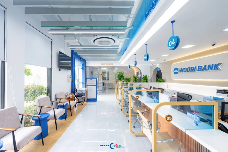 Quầy giao dịch Woori Bank tông trắng xanh với bảng số quầy treo trần, thiết kế văn phòng công ty hiện đại