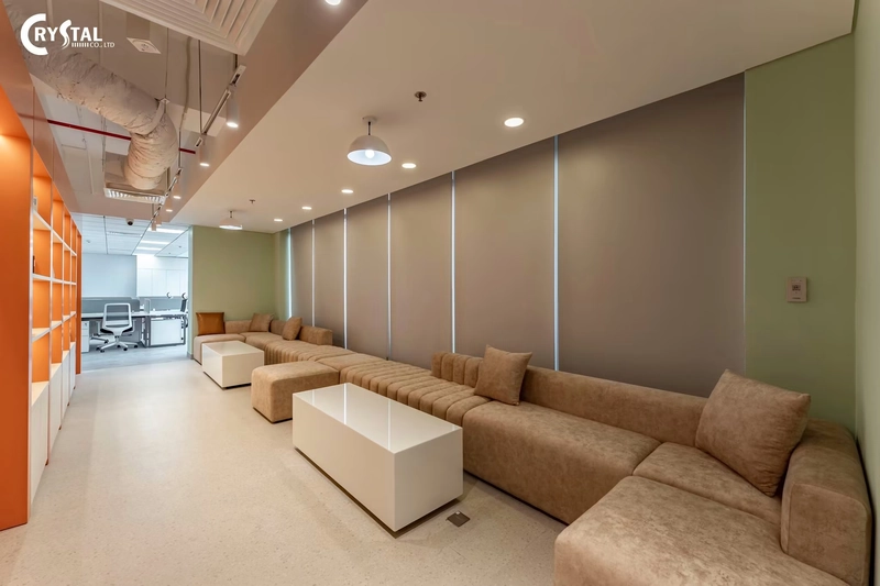 Khu nghỉ với sofa nâu dài, bàn trà trắng và mảng tường xanh rêu, nội thất văn phòng đẹp và êm dịu