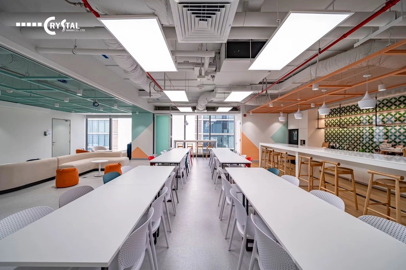Khu pantry bàn trắng dài, quầy bar gỗ và mảng tường họa tiết xanh, nội thất văn phòng hiện đại tiện nghi