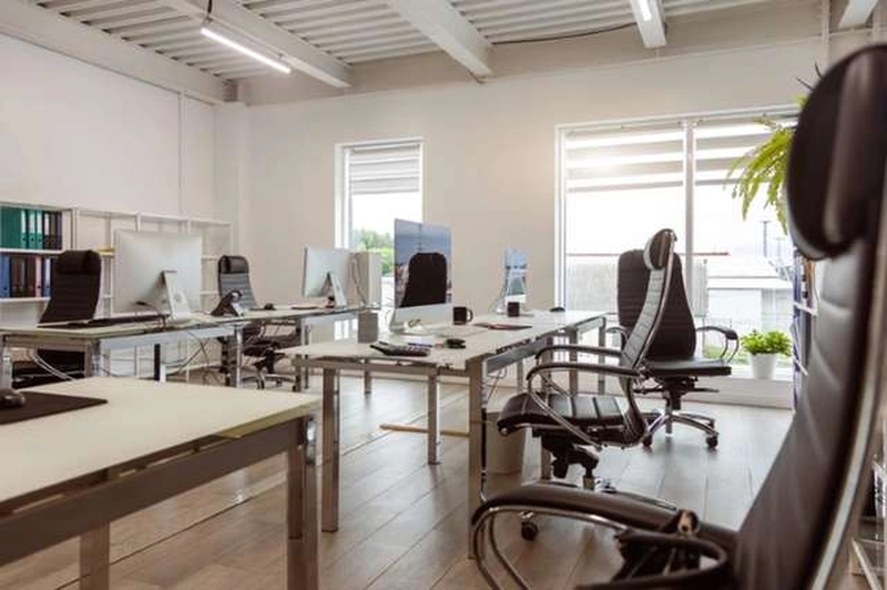 Văn phòng 70m2 tông trắng với bàn khung thép, ghế lưới đen và sàn gỗ sáng màu