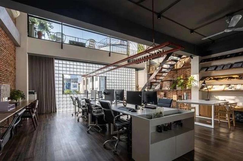 Tường gạch mộc, gác lửng khung thép và sàn gỗ sẫm trong mẫu thiết kế văn phòng 70m2 công nghiệp